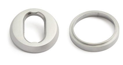 Två silverfärgade cylinderformade metallringar med olika öppningar, en oval och en rund.