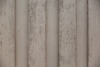 Beige vertikalt räfflad yta med ojämnheter och fläckar.