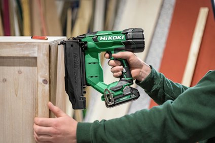 Grön spikpistol av märket HiKOKI används av en person för att fästa träytor.