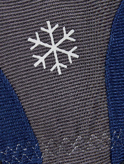Grå och blå stickat tyg med ett vitt snöflingemotiv och dekorativa sömmar.